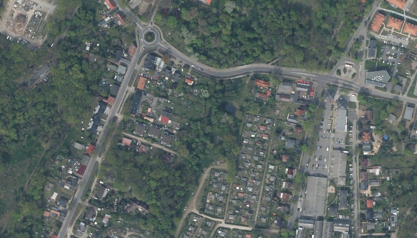 Luftbild einer Ortsmitte: Kreisverkehr, Durchgangsstraße, gemischte Bebauung aus Wohnhäusern und kleinen Gewerbebauten.